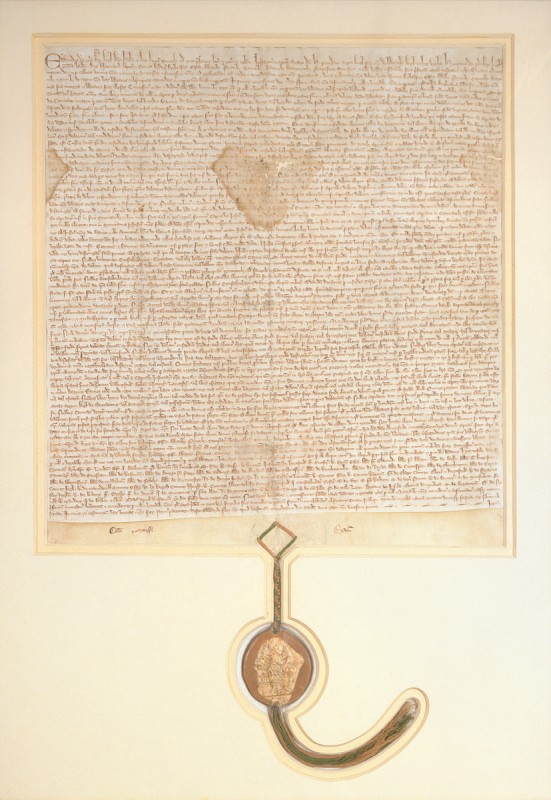 The 1297 Magna Carta. The rectangular document is covered in very small, old-style writing. A seal hangs from the bottom.