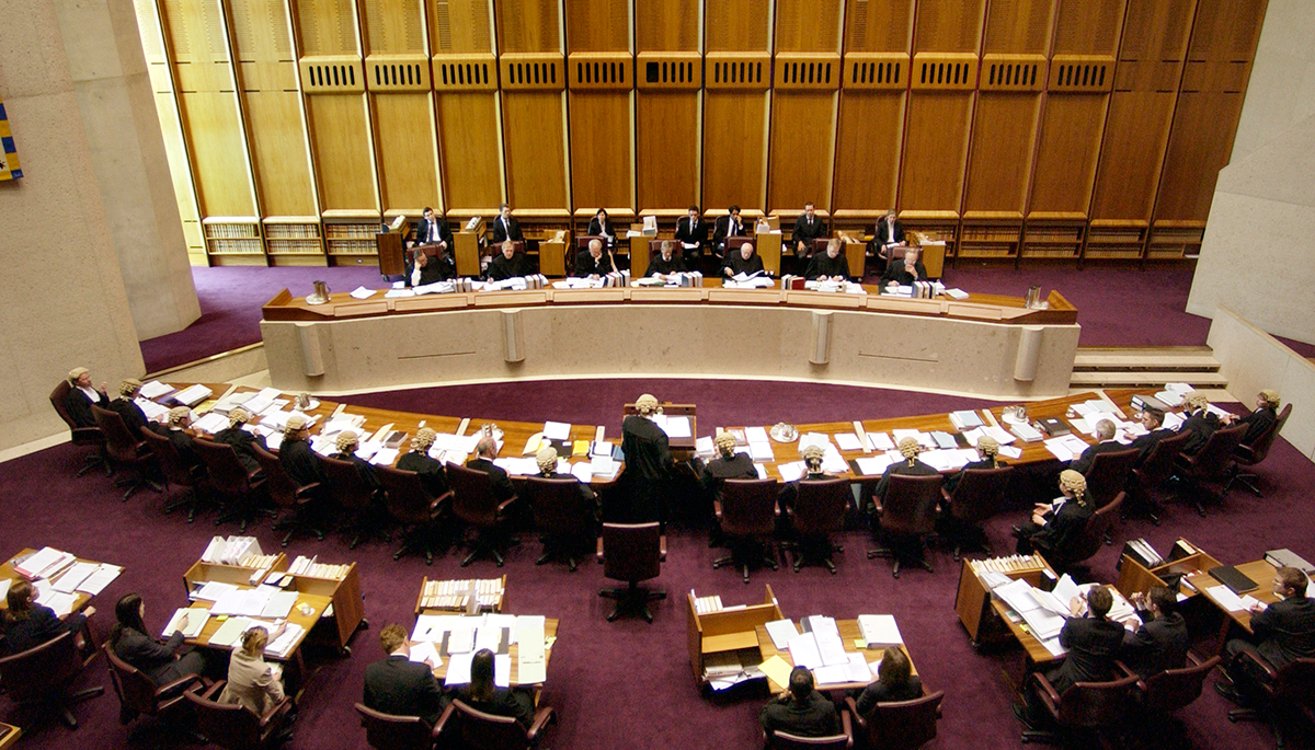 The Australian High Court in session with judges sitting at a long table and lawyers sitting at another table facing them.