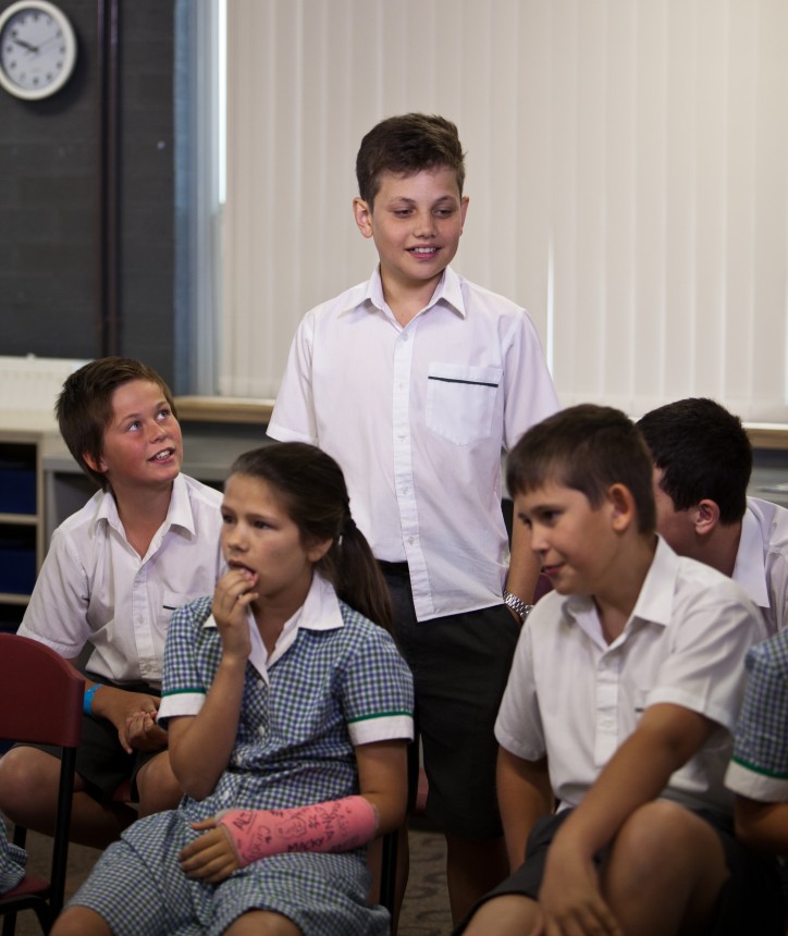 This image shows a group of students in a classroom. One is standing.